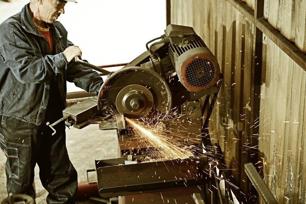 Industrial worker cutting and welding metal with many sharp sparks